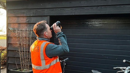 Onderzoeker bekijkt gevel met verrekijker
