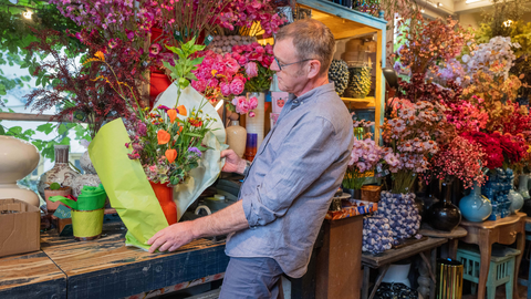 Bloemist die een bos bloemen inpakt.